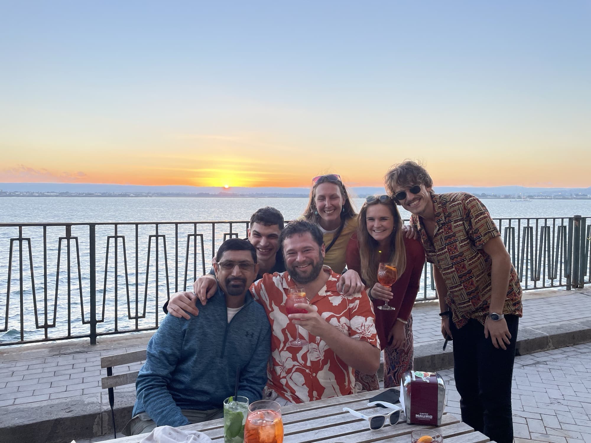 Friends sharing drinks at sunset by the water